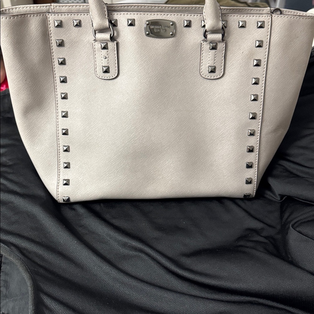 Michael Kors grey bag with silver metal studding on front.
